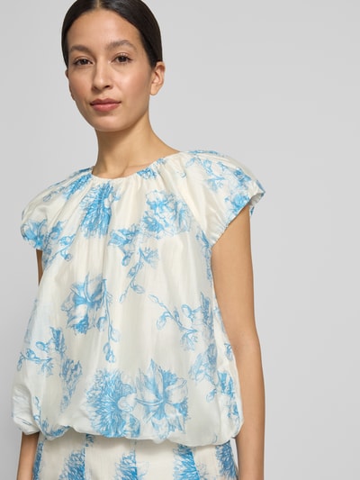 Frauenmodel trägt Regular Fit Bluse aus Lyocell-Mix Modell 'Evangelia' von MSCH Copenhagen mit floraler Allover-Print, Falten-Optik, in Creme und Blau, kurzärmelig, Rückenlänge 50 cm bei Größe S, Nahaufnahme Oberkörper.