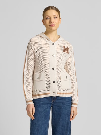 Frauenmodel trägt Regular Fit Strickjacke mit Kapuze von monari aus Reine Baumwolle mit Lochmuster, Logo-Detail, AufgesetzteTaschen, Elastische Abschlüsse, durchgehende Knopfleiste, Zierbesatz, creme mit braunen Akzenten, Strukturmix, Ganzkörperansicht von vorne.