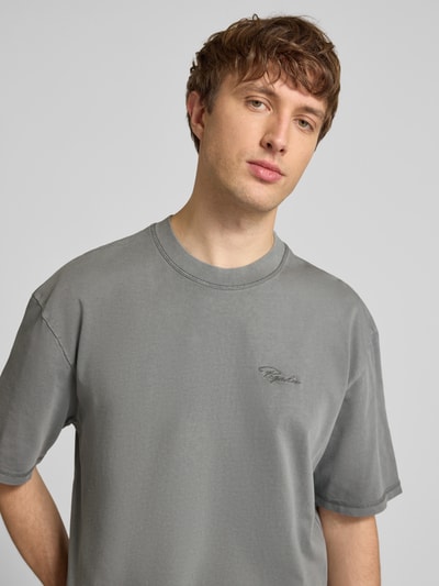 Männermodel trägt Oversized Fit T-Shirt mit Logo-Stitching von Pegador in Grau, Reine Baumwolle, Rundhalsausschnitt, Nahaufnahme Oberkörper.