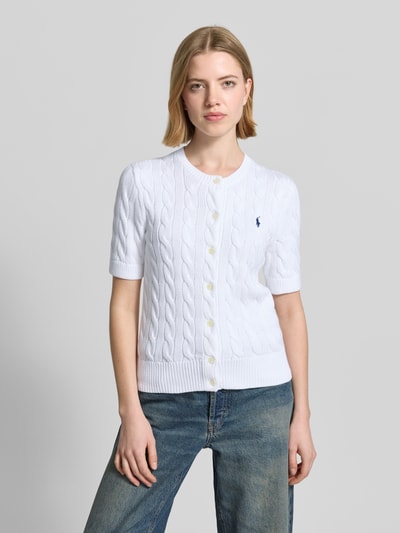 Frauenmodel trägt Regular Fit Strickjacke aus reiner Baumwolle von Polo Ralph Lauren, Optik: Unifarben, Zopfmuster, Logo-Stitching, Kragenform: Crew Neck, Ärmelform: Kurzarm, Ärmelabschluss: Gerippt, Rumpfabschluss: Gerippt, Materialverarbeitung: Strick, Ganzkörperansicht von vorne.