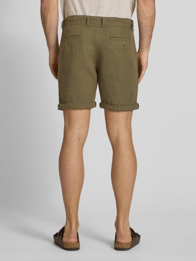 Männermodel trägt Leinenshorts mit Bindegürtel und Gesäßtaschen von MCNEAL in Oliv, reines Leinen, Ganzkörperansicht Rückansicht. Kontext: Straight Fit, Knopf- und Reißverschluss, Bindegürtel, französische Eingrifftaschen, Saum mit Aufschlag, Gesäßleistentaschen mit Knopfverschluss, rückseitiges Label-Stitching, Bundweite bei Größe M: 45 cm, Innenbeinlänge bei Größe M: 16 cm.
