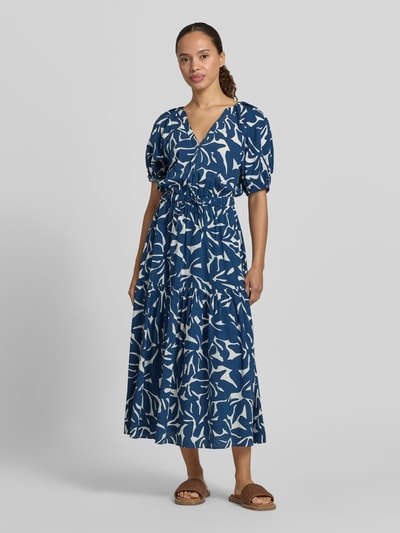 Frauenmodel trägt Midikleid aus Viskose-Baumwoll-Mix mit V-Ausschnitt von Zero, blau-weißes Allover-Muster, A-Linie, Bindegürtel, Ganzkörperansicht von vorne.