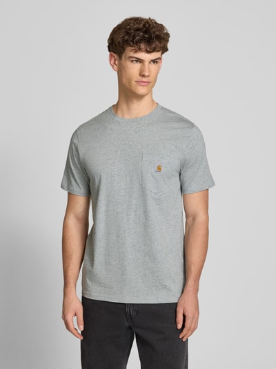 Männermodel trägt Regular Fit T-Shirt mit Logo-Patch von Carhartt Work In Progress in Grau aus Reine Baumwolle, Brusttasche, Rundhalsausschnitt, Rückenlänge 70 cm, Ganzkörperansicht von vorne.