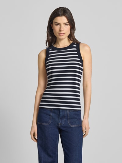 Frauenmodel trägt Tanktop mit Rippenstruktur Modell 'OLINA' von Drykorn aus Reine Baumwolle, eng anliegender Schnitt, Rundhalsausschnitt, Rückenlänge 55 cm bei Größe S, gestreiftes Design, Ganzkörperansicht von vorne.