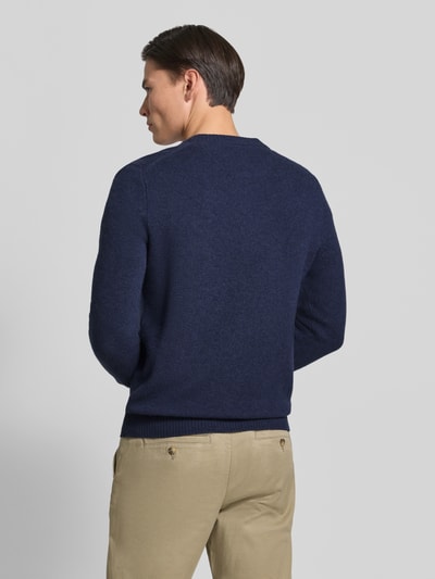 Männermodel trägt Regular Fit Strickjacke aus reiner Wolle mit Logo-Stickerei von MCNEAL in Dunkelblau, Detail: gerippte Abschlüsse, Rückenansicht, Ganzkörperansicht Rückansicht
