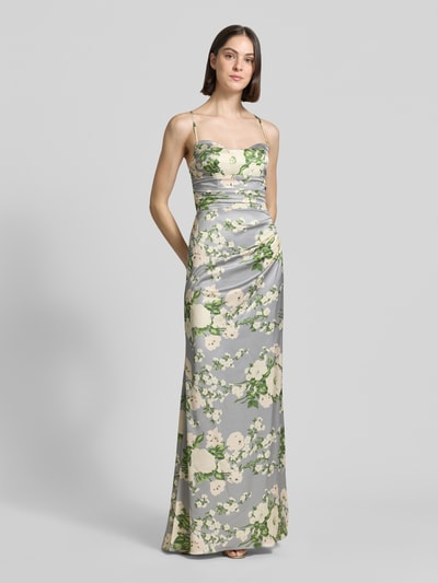 Vrouwenmodel draagt 'Abendkleid mit rückseitiger Schnürung' van Mascara, satijnen maxi-jurk in lichtgrijs met groene en crèmekleurige bloemen, aansluitende fit, waterfall-halslijn, gekruiste spaghetti-bandjes en draperingen achter, detailopname, Ganzkörperansicht van voren.
