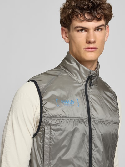 Männermodel trägt silbergraue Weste mit Logo und Stehkragen Modell 'HALO SABER' von HALO, Regular-Fit, Reißverschluss, Nahaufnahme Oberkörper. Rückenlänge 68 cm, Schulterbreite 40 cm, Brustweite 37 cm.