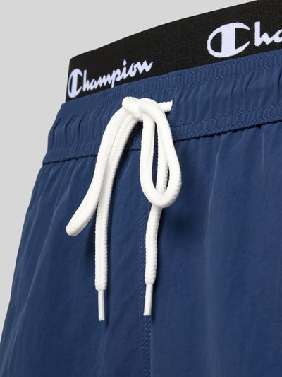 Männermodel trägt Badehose mit Label-Details und Gesäßtasche von CHAMPION, Regular Fit, elastischer Bund, Tunnelzug, Nahaufnahme Oberkörper.