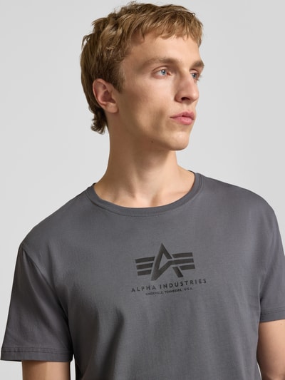 Männermodel trägt T-Shirt mit Logo und Rundhalsausschnitt von Alpha Industries aus reiner Baumwolle, Regular Fit, Nahaufnahme Oberkörper.