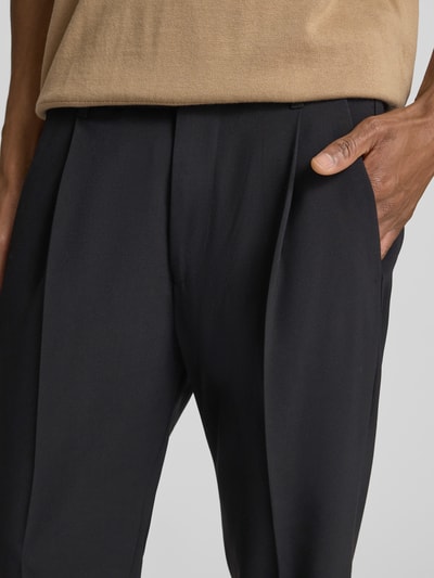 Männermodel trägt Hose mit Eingrifftaschen Modell 'CHASY' von Drykorn in Schwarz, Material-Mix, Nahaufnahme Oberkörper, Kontext: Herren Hose, Tapered Fit, elastischer Bund, französische Eingrifftaschen, Gesäßleistentaschen, Knopf- und Reißverschluss, Bundweite 42 cm, Innenbeinlänge 66 cm.