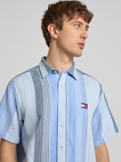 Männermodel trägt Relaxed Fit Freizeithemd aus reiner Baumwolle von Tommy Jeans mit Optik:Allover-Muster, gestreift, Nahaufnahme Oberkörper.