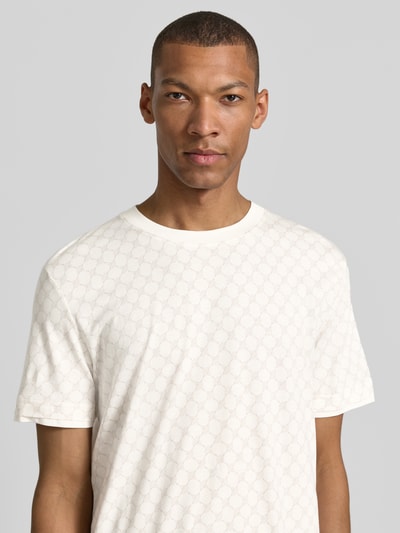Męski model nosi T-Shirt mit Logo-Muster und Rundhalsausschnitt von JOOP! Collection z bawełny i lyocellu, krój regular fit, biała z subtelnym wzorem, widok na górną część ciała z przodu.