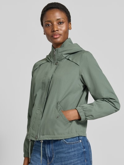 Frauenmodel trägt Regular Fit Parka mit Kapuzenkragen Modell 'ZOA' von VERO MODA in mattem Grün, sichtbare Taschen, Ganzkörperansicht von vorne.