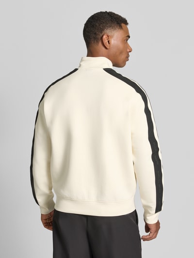 Männermodel trägt Regular Fit Sweatjacke aus Baumwoll-Mix Modell 'Felpa' von Armani Exchange in Beige mit schwarzen Details, Ganzkörperansicht Rückansicht. Elastischer Baumwoll-Mix, Stehkragen, Zweiwege-Reißverschluss, Eingrifftaschen, elastische Abschlüsse.