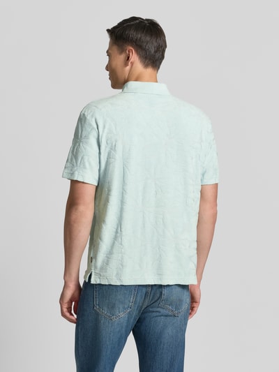 Männermodel trägt Regular Fit Poloshirt aus Baumwoll-Mix Modell 'PE_FLOWER' von BOSS Orange, Optik:Allover-Muster, Struktur, Ganzkörperansicht Rückansicht.