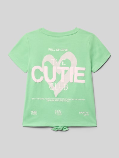 Meisje draagt Regular Fit T-shirt uit puur katoen van s.Oliver RED LABEL, look: effen, pasvorm: regular fit, applicatie met statementprint, strikdetail, ronde hals, korte mouw, materiaalverwerking: jersey, materiaal: puur katoen, mintgroen met witte tekst, ganzkörperansicht rückansicht.