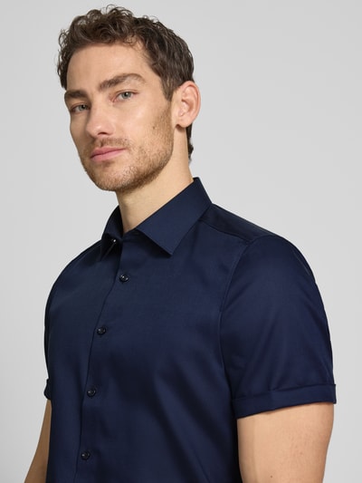 Męski model nosi Slim Fit Business-Hemd mit Kentkragen od OLYMP Level Five, granatowy, gładka bawełna, krój slim fit, guzik, kołnierz kent, rękawy z mankietami, długość pleców w rozmiarze 40: 70 cm, szerokość w rozmiarze 40: 40 cm, długość rękawa w rozmiarze 40: 24 cm, zbliżenie na górną część ciała