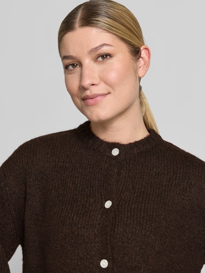 Frauenmodel trägt Cardigan mit Alpaka-Anteil und Rundhalsausschnitt Modell 'OTIA' von b.young in Dunkelbraun, grobe Textur, Nahaufnahme Oberkörper. Regular Fit, Knopfleiste, weiche Oberfläche.