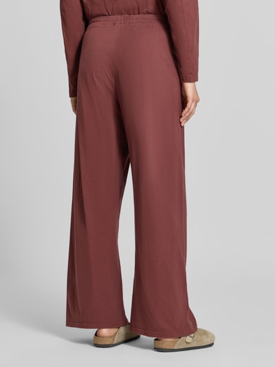 Frauenmodel trägt Wide Fit Hose aus reiner Baumwolle Modell 'GIXY' von American Vintage in Braun mit elastischem Bund, Ganzkörperansicht Rückansicht.