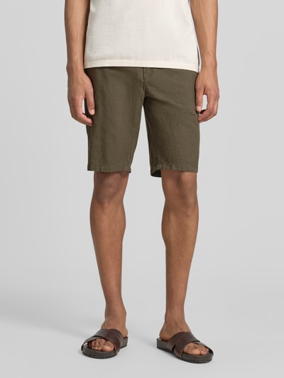 Männermodel trägt Bermudas aus Leinen-Mix mit französischen Eingrifftaschen von Lindbergh in Oliv, Struktur fein, Ganzkörperansicht von vorne. Bundweite bei Größe M: 43 cm, Innenbeinlänge 24 cm, Leinen-Baumwoll-Mix, Straight, Elastischer Bund mit Kordelzug, Knopf- und Reißverschluss, Gesäßtaschen.