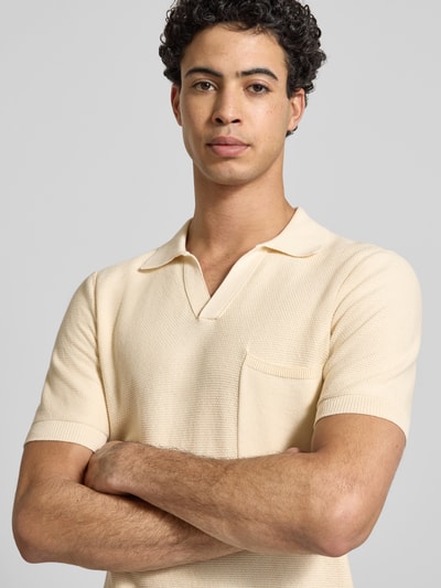 Mężczyzna nosi Slim Fit Poloshirt in Strick-Optik od Replay w kolorze kremowym, krój slim fit, czysta bawełna, krótki rękaw, tekstura dzianiny, kieszeń na piersi, detal z logo, Szerokość w rozmiarze M: 69 cm, Nahaufnahme górnej części ciała.