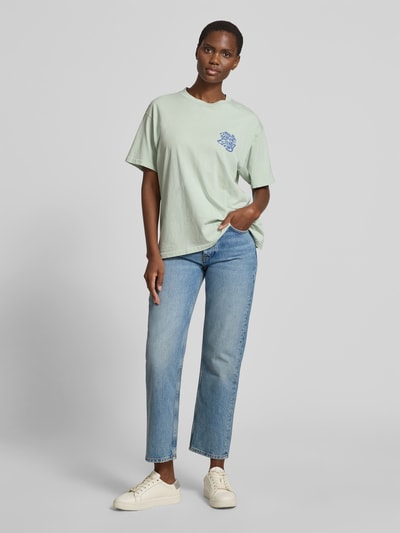 Frauenmodel trägt Damen T-Shirt von Anine Bing aus Reine Baumwolle, Straight Fit, Jeans im 5-Pocket-Design, verkürzte Passform, Ganzkörperansicht von vorne.