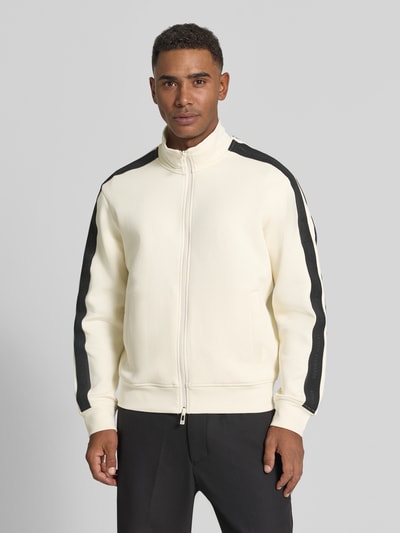 Männermodel trägt Regular Fit Sweatjacke aus Baumwoll-Mix Modell 'Felpa' von Armani Exchange in Creme mit schwarzen Streifen, Nahaufnahme Oberkörper. Elastischer Baumwoll-Mix, Zweiwege-Reißverschluss, Eingrifftaschen, elastische Abschlüsse.