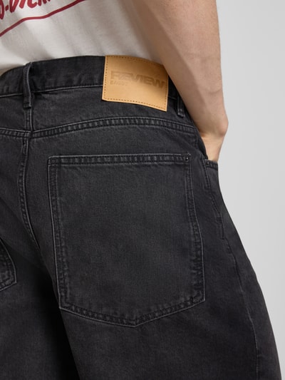 Männermodel trägt Jeansshorts mit Eingrifftaschen von REVIEW, schwarze Baumwolle, Relaxed Fit, Used-Look, Nahaufnahme Rückansicht.
