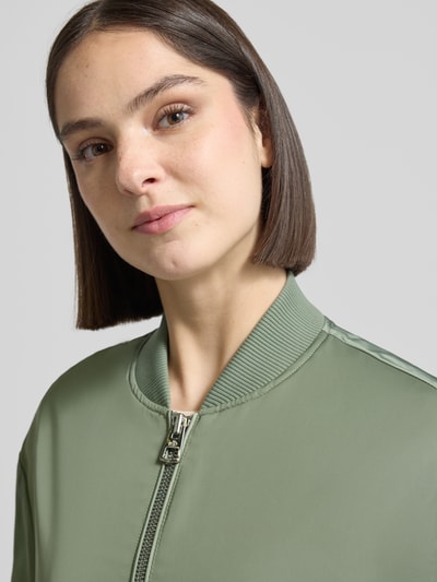 Kobieta-modelka nosi Regular Fit bluzon-płaszcz z college'owym kołnierzem od Marc O'Polo, efekt: jednolity kolor, satynowe wykończenie, naszywka z logo, długi rękaw, elastyczne zakończenie rękawów, wpuszczane kieszenie boczne, kieszeń wewnętrzna, zamek błyskawiczny dwustronny, zbliżenie na górną część ciała