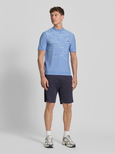 Männermodel trägt Regular Fit T-Shirt aus Viskose-Mix Modell 'KN_Globe TS' von BOSS Green in Strickoptik, hellblau, Label-Schriftzug, Ganzkörperansicht von vorne.