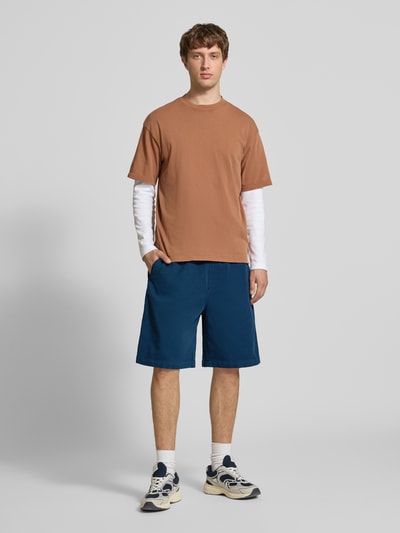Männermodel trägt Shorts mit Gesäßtasche Modell 'Floyde' von Carhartt Work In Progress aus Lyocell-Mix, Loose-Fit, Bundweite 37 cm, Innenbeinlänge 24 cm, Ganzkörperansicht von vorne.