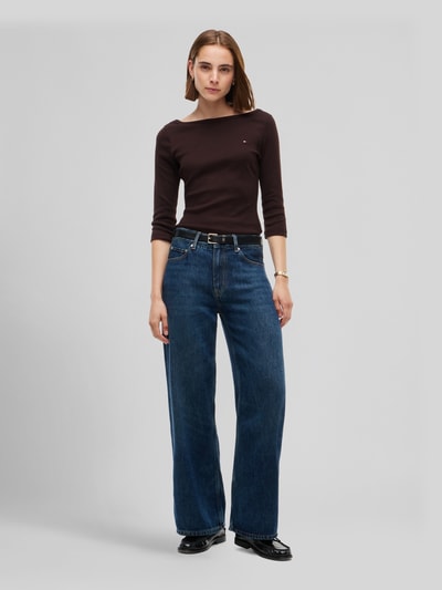 Frauenmodel trägt Slim Fit Langarmshirt aus reiner Baumwolle von Tommy Hilfiger in Dunkelbraun mit glatter Textur, Ganzkörperansicht von vorne, Damen T-Shirt von Tommy Hilfiger.