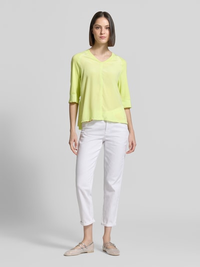 Modelka kobieca nosi damski t-shirt z dekoltem w serek i rękawem o dł. 3/4 od Marc Cain, mieszanka bawełny i elastanu, krój relaxed fit, długość tyłu w rozmiarze 36: 60 cm, pastelowa żółć, proste kształty, gładka tekstura, pełen widok sylwetki z przodu.