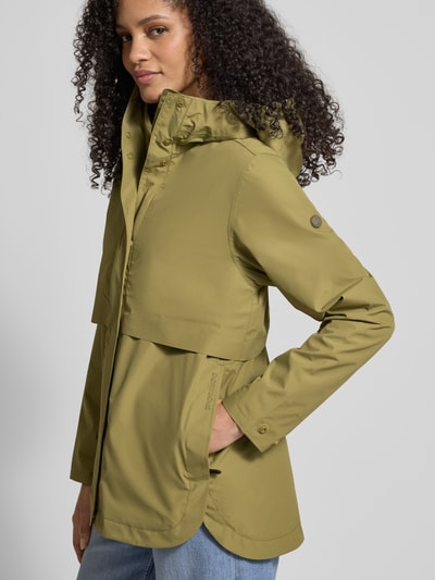 Frauenmodel trägt Regular Fit Funktionsjacke mit Kapuze Modell 'Elsa' von Didriksons in Olivgrün, glatte Oberfläche, Ganzkörperansicht von vorne. Rückenlänge 74 cm, Schulterbreite 42 cm, Brustweite 37 cm, Ärmellänge 63 cm.