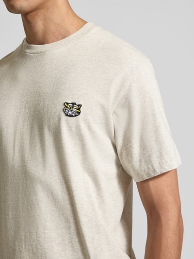 Männermodel trägt Regular Fit T-Shirt aus reiner Baumwolle von Kenzo in Beige mit Label-Patch, Rundhalsausschnitt, Kurzärmelig, Nahaufnahme Oberkörper.