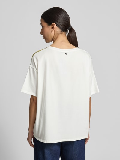 Frauenmodel trägt Relaxed Fit Blusenshirt aus Baumwoll-Mix Modell 'PAMPAS' von Weekend Max Mara in Weiß, Ganzkörperansicht Rückansicht. Baumwoll-Popeline, kurzer Ärmel, florales Allover-Muster, Logo-Print am Rücken, Rundhalsausschnitt, lockere Passform.