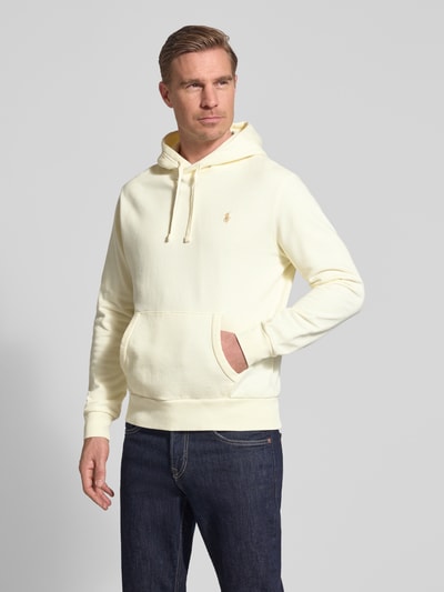 Mannelijk model draagt Relaxed Fit Hoodie uit reiner Baumwolle van Polo Ralph Lauren in effen lichtgeel met logodetail, kangoeroezak, capuchon met tunnelkoord, lange mouwen met geribde boorden en rompzoom, sweat materiaal, puur katoen. Ganzkörperansicht van voren.