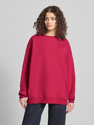 Frauenmodel trägt Oversized Sweatshirt mit Logo-Stitching Modell 'Toast' von OH APRIL, satter Rotton, Baumwoll-Mix, Ganzkörperansicht von vorne.