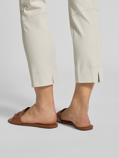 Kobieta nosi Schmale Schlupfhose aus Techno Cotton Superstretch von Raffaello Rossi, krój slim fit, skrócony, model 'PENNY 6/8', szerokość w rozmiarze 36: 36 cm, długość wewnętrzna nogawki w rozmiarze 36: 61 cm, jasny kolor, gładka faktura, detal spodni, widok na dolną część nogawek, z tyłu