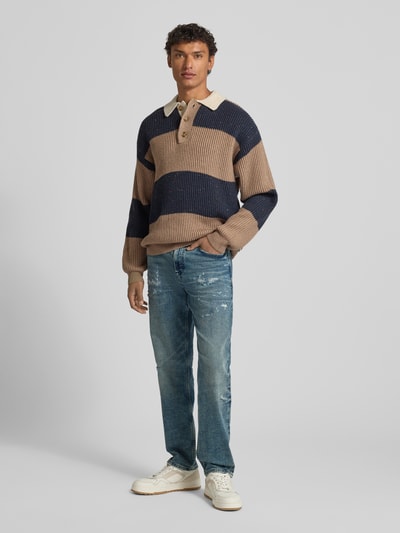 Männermodel trägt Tapered-Fit Jeans aus Baumwoll-Mix Modell 'TROY' von BOSS Orange in Denim-Optik mit Destroyed-Details, 5-Pocket-Design, Ganzkörperansicht von vorne.