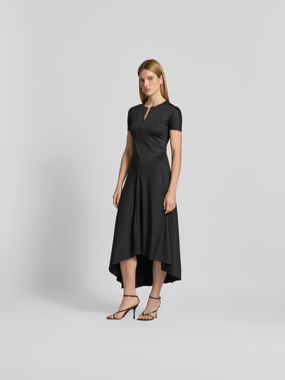 Frauenmodel trägt schwarzes Midikleid mit verlängerter Rückseite von Victoria Beckham, elastischer Material-Mix, Kurzarm, Frontreißverschluss, Ganzkörperansicht von vorne.