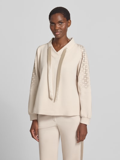 Frauenmodel trägt Sweatshirt mit Kapuze von MARC CAIN in Beige, unifarben mit Strukturmuster, langen Ärmeln und Kordeln, Nahaufnahme Oberkörper.