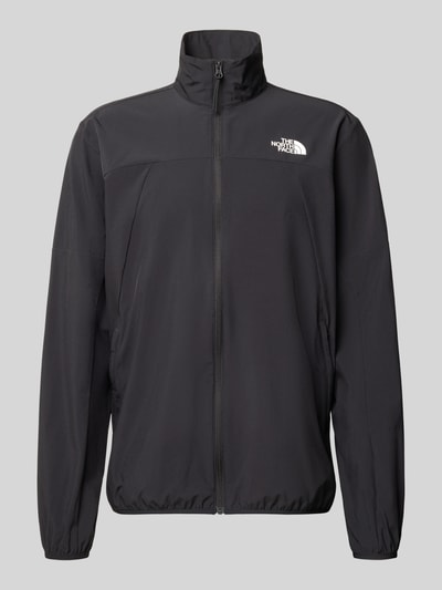 Produktfoto, czarna kurtka Regular Fit Jacke mit Stehkragen Modell 'Mountain' od The North Face, elastyczna mieszanka materiałów, nadruk z logo, zamek błyskawiczny, wpuszczane kieszenie, elastyczne wykończenia, długość tyłu w rozmiarze M: 73 cm, szerokość ramion w rozmiarze M: 43 cm, szerokość klatki piersiowej w rozmiarze M: 56 cm, długość rękawów w rozmiarze M: 70 cm