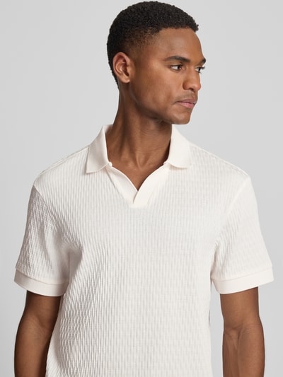 Männermodel trägt Regular Fit Poloshirt mit V-Ausschnitt Modell 'Rauljose' von JOOP! Collection aus reiner Baumwolle mit Strukturmuster, Nahaufnahme Oberkörper.