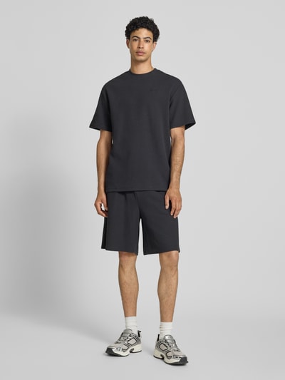 Männermodel trägt Oversized T-Shirt mit Strukturmuster und Logo-Stitching von KARL KANI aus Baumwoll-Mix, Oversized-Fit, Rundhalsausschnitt, Rückenlänge 75 cm in Größe M, Herren T-Shirt, Ganzkörperansicht von vorne.