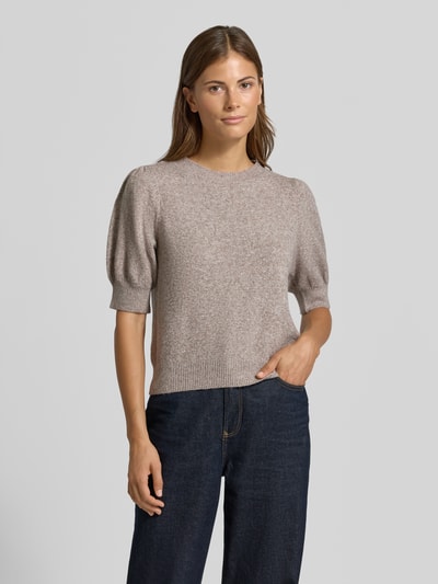 Frauenmodel trägt Regular Fit Pullover mit Puffärmeln von VERO MODA, beige meliert, glatte Textur, dazu dunkelblaue Hose, Ganzkörperansicht von vorne.