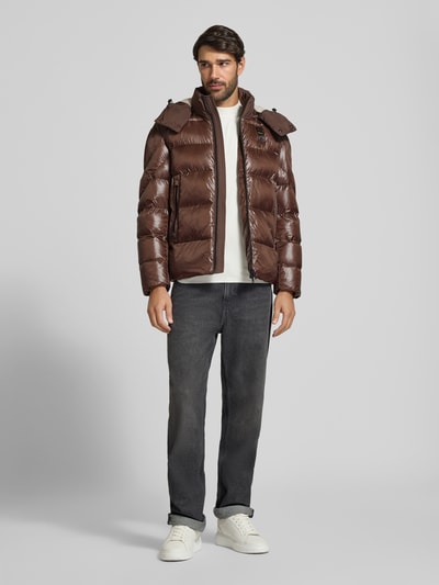 Männermodel trägt Steppjacke mit Zweiwege-Reißverschluss Modell 'KIERNAN' von Blauer USA, braun, glatte Struktur, krój regular fit, Ganzkörperansicht von vorne, długość tyłu w rozmiarze M: 67 cm, szerokość w ramionach w rozmiarze M: 49 cm, szerokość w klatce piersiowej w rozmiarze M: 59 cm, długość rękawa w rozmiarze M: 65 cm