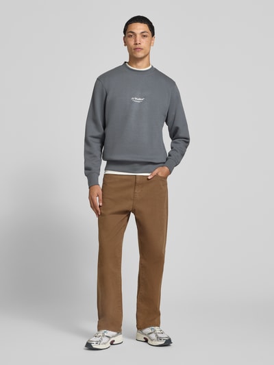Männermodel trägt Regular Fit Sweatshirt aus Baumwoll-Mix Modell 'Soho' von JACK & JONES in Grau mit Logo-Print und Rundhalsausschnitt, Ganzkörperansicht von vorne. Rückenlänge bei Größe M: 65 cm, Ärmellänge: 66 cm, elastische Abschlüsse.