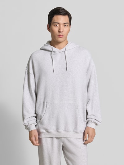 Männermodel trägt Hoodie mit Känguru-Tasche Modell 'ATUBAY' von American Vintage in Hellgrau, Baumwoll-Elasthan-Mix, Relaxed-Fit, Ganzkörperansicht von vorne.