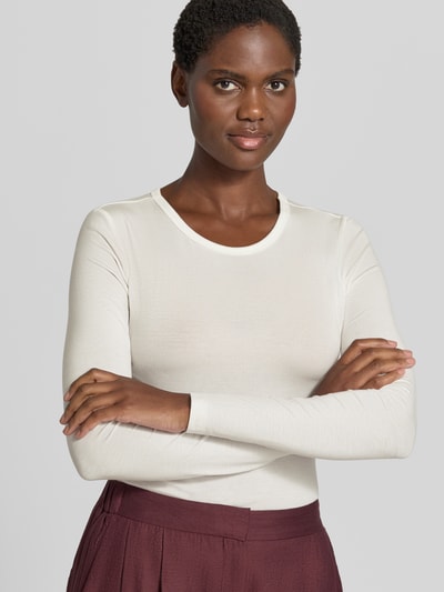 Frauenmodel trägt weißes Slim Fit Langarmshirt aus Lyocell-Mix Modell 'ADA' von VERO MODA, kombiniert mit bordeauxfarbener Hose, Nahaufnahme Oberkörper, Damen Langarmshirt von VERO MODA.
